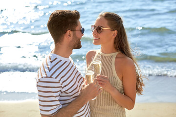 leisure, relationships and people concept - happy couple in sunglasses drinking champagne on summer beach