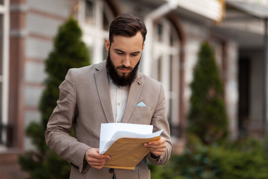 The entrepreneur and the project proposed to him. The lawyer reads the contract.carefully. A man and an envelope of documents.