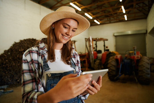 Caucasian female farmer smiling standing in shed holding digital tablet