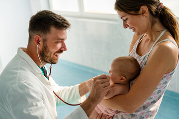 Happy pediatrician doctor with baby checking possible heart defect