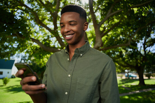 Mixed race male farmer standing outdoors smiling at cellular device