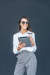 Young business woman with coffee and tablet on grey background.