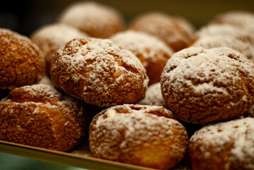 mouth-watering delicious custard buns with powder on top on the showcase close-up