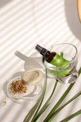 Spray bottle in glass near clay powder in plate and solid soap.