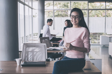 Portrait of asian business woman who standing in feeling happy at the office with daylight from window and blur garden background.