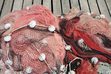 Rote Fischernetze aus Nylon auf alten Holzstegen im Sommer bei Sonnenschein in der Altstadt am...