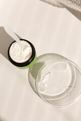 Jar of cosmetic clay powder with spoon and plate with water.