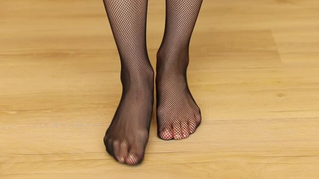 A female wearing black net tights moving her feet on a wooden floor - shot in HD