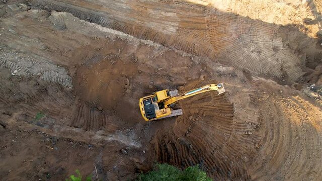 Excavator on earthworks. Arial view of the groundwork on construction site. Mining heavy equipment on foundation pit construction. Dig ground for laying sewer concrete pipes. Open pit mine develop.