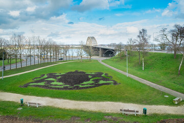 Naklejka premium View of the Waalbrug near Nijmegen in the foreground is the coat of arms of Nijmegen cut out in the grass, Nijmegen, Gelderland Province, The Netherlands