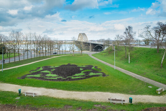 View of the Waalbrug near Nijmegen in the foreground is the coat of arms of Nijmegen cut out in the grass, Nijmegen, Gelderland Province, The Netherlands