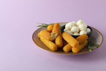 Plate with cheese sticks, mozzarella and rosemary on violet background