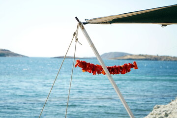 Rot schimmernde Dekoration am Gestänge eines Vorzelt mit Blick auf die Bucht vor Foca im Sommer...