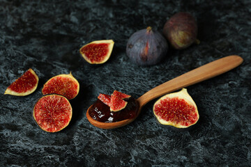 Spoon with fig jam and ingredients on black smokey background