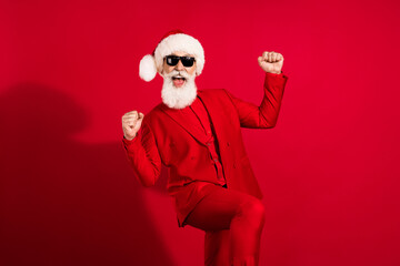 Portrait of attractive bearded cheerful grey-haired man wearing costume dancing rejoicing isolated over bright red color background