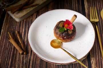 roasted red apples with cinnamon and honey in white earthenware dish on dark wooden table