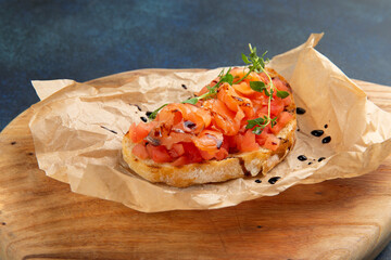 bruschetta with salmon and tomatoes. Against a dark background.