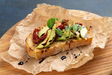 bruschetta with avacado and sun-dried tomatoes. Against a dark background.