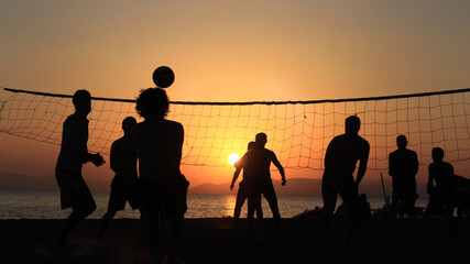 Beach Volleyball Silhouette on Sunset. Young men playing volleyball on the beach on sunset. Cinematic view. Action shot