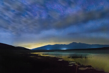 Fototapeta premium Sunset over the lake. Evening sky with clouds and stars over the lake.