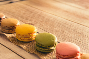 Dessert of French macarons in pastel colors on wood. Copy space. Selective focus.