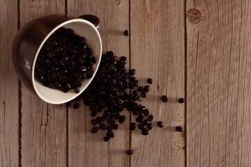 Overturned coffee cup with coffee beans. Copy space. Selective focus.