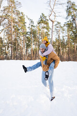 Young couple in winter outfit having fun in park with snow