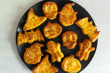 Step-by-step preparation of cottage cheese muffins for Halloween. Sweet cupcakes with monsters for children on a black plate. Top view. Baking in the form of a hat, a skull, a ghost, a pumpkin.