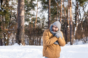 Fototapeta na wymiar Smiling man in warm clothes standing in winter park