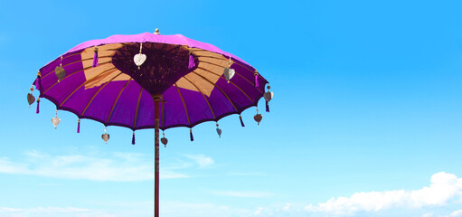 Traditional colorful Balinese umbrella on blue sky background