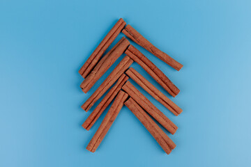 cinnamon sticks in the shape of a fir tree on blue background. Christmas composition, copy space.