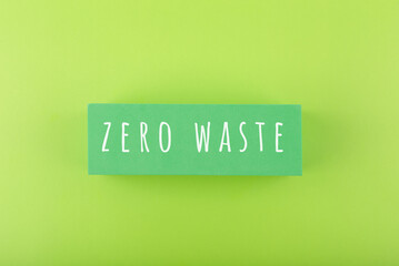 Modern minimal flat lay with zero waste inscription against light green background. Concept of go green, recycle, reduce, reuse and eco friendly lifestyle