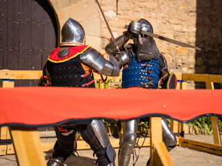 caballeros medievales batiendose en duel, caballero azul atacando torneo profight en castillo de montonis lleida cataluña españa