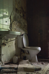 Old dirty broken toilet and sink in a dilapidated bathroom.