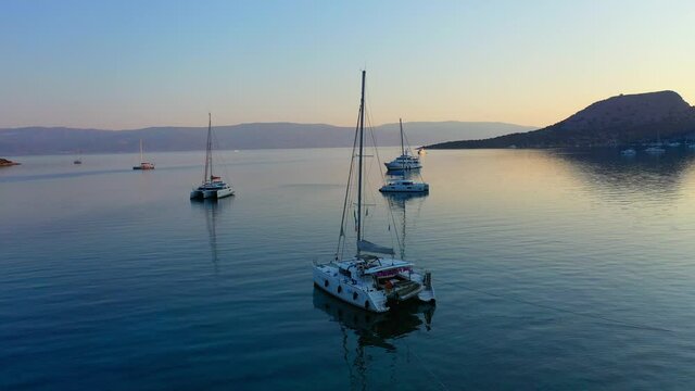 Catamaran and sail Yachts anchored at bay on deep blue sea water on sunrise