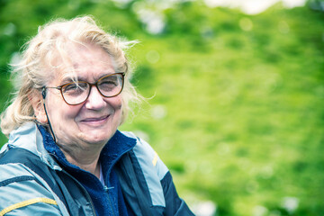 Happy elderly woman relaxing in the middle of a mountain trip.