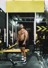 Fototapeta na wymiar Strong man standing in a gym with satisfaction expression