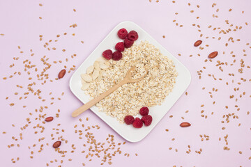 Wheat flakes, pumpkin seeds and raspberries in plate. Wheat grains on table