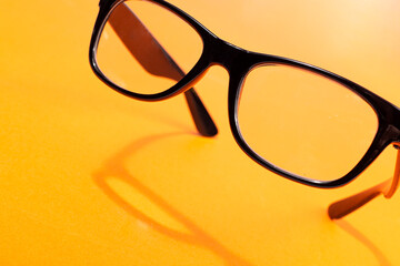 flying black glasses with shadow on orange background.