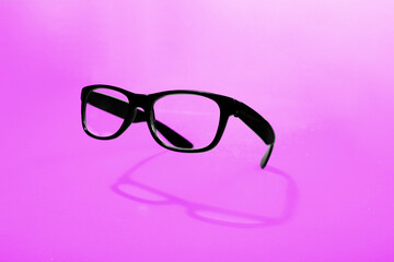 flying black glasses with shadow on pink background.