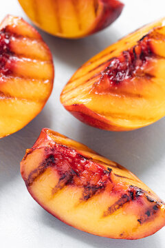 Juicy grilled nectarine quarters on light gray cutting board. Top view. Selective soft focus. Abstract food background.