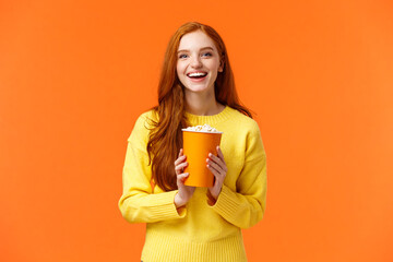 Cheerful cute redhead curly girlfriend holding popcorn chat with boyfriend before movie start at...