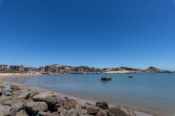 Stand high and watch the sea scenery under the blue sky, blue water, white waves and black rocks