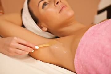 Beautician waxing female armpits in spa center