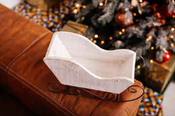 A festive sleigh decor piece in front of a Christmas tree, highlighting the joy and coziness of the holiday celebration.