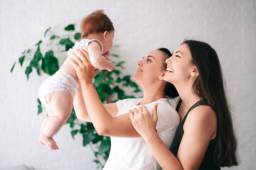 A young happy female couple and their child are enjoying together at home. lesbian couple