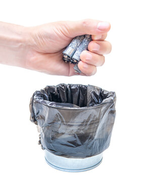 Male tossing dead corroded batteries in a regular garbage bin