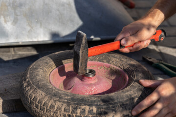 Close-up of a man's hand changes the wheel bearing in a garden wheelbarrow