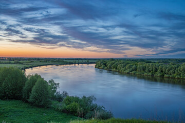 Beautiful evening panorama landscape with river, distance, meadows and fields on the horizon.