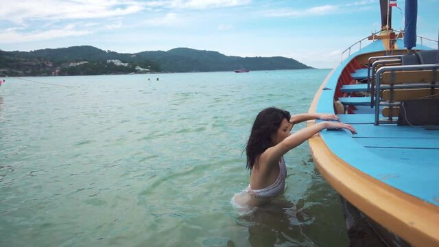 Woman jump into long tail boat. Tourism and recreation in Thailand. Charming cute Asian woman travel around the islands. The girl enjoy life and has fun. Paradise beaches and white sand